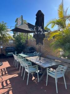 una mesa y sillas de madera con sombrilla, mesa y sillas en Forster Palms Motel, en Forster