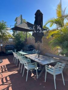 a wooden table and chairs with an umbrella and a table and chairs at Forster Palms Motel in Forster