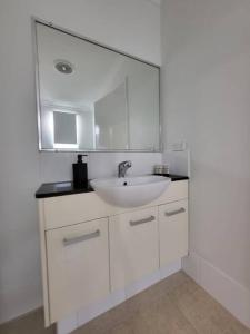 a white bathroom with a sink and a mirror at Cosy modern townhouse - 5 mins walk to the beach! in Wannanup