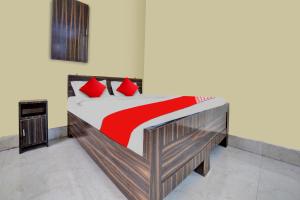 um quarto com uma cama de madeira e almofadas vermelhas em OYO Flagship Prakash Inn em Jamshedpur