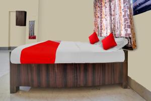 Bett mit roten Kissen in einem Zimmer in der Unterkunft OYO Flagship Prakash Inn in Jamshedpur