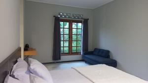 GubukklakahMountain Ecolodge的一间卧室，有一张床和一把蓝色椅子