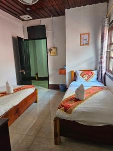 a bedroom with two beds and a door to another room at Chitlatda Bila House in Luang Prabang