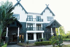 a large white house with black windows at Trung Nguyên Coffee Resort in Buon Ma Thuot
