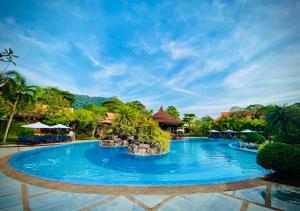 une piscine dans un complexe avec de l'eau bleue et des palmiers dans l'établissement Try Palace Resort Kep, à Kep