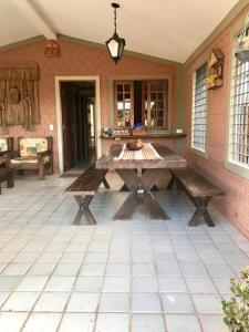 a wooden picnic table on a patio with benches at Casa Santa Paz - Gravata, próximo ao Centro in Gravatá