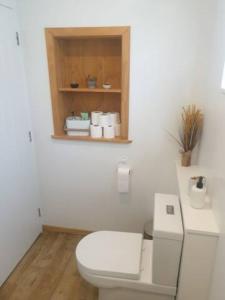 een badkamer met een wit toilet en een houten kast bij New, Cosy & Private 1-Bedroom & Living Flat in Porirua