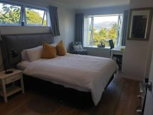 a bedroom with a large bed with two windows at New, Cosy & Private 1-Bedroom & Living Flat in Porirua