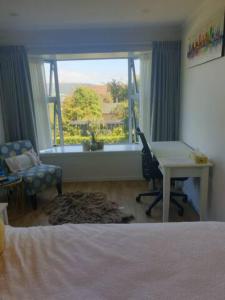 a bedroom with a bed and a desk and a window at New, Cosy & Private 1-Bedroom & Living Flat in Porirua