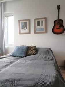 a bedroom with a bed and a guitar on the wall at Toppilansalmi two bedroom apartment with a view in Oulu