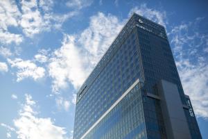 a tall glass building with a cloudy sky in the background at THE BLOSSOM HIBIYA in Tokyo