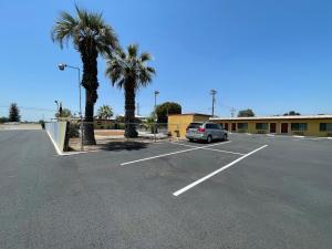 a car parked in a parking lot with palm trees at Kings Rest Motel in Lemoore