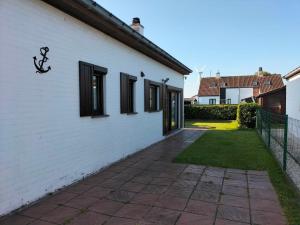 een wit huis met zwarte ramen en een loopbrug bij Aux 3 P'tits Wallons in Middelkerke