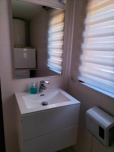 een badkamer met een witte wastafel en een spiegel bij Aux 3 P'tits Wallons in Middelkerke