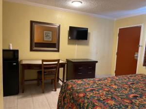 a hotel room with a desk and a bed and a table at Kings Rest Motel in Lemoore
