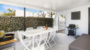 a patio with a white table and chairs and a grill at Coastal Vibes Minutes To Beach - Pet Friendly in Salamander Bay