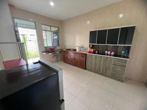 a large kitchen with wooden cabinets and a black refrigerator at Leng Leng Homestay in Sibu