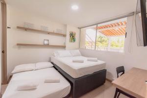 2 camas en una habitación con mesa y ventana en Apartasol Dominica Citadela Di Sole, en Santa Fe de Antioquia