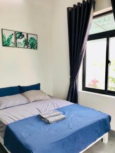 1 dormitorio con cama con sábanas azules y ventana en Tammy homestay- Ganh Da Dia, en Tuy An
