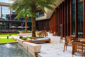 海口的住宿－海口萬麗酒店，一间设有桌椅的餐厅,种植了棕榈树