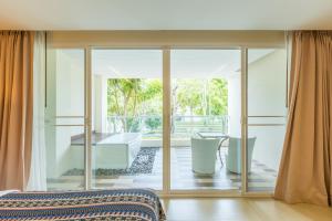a bedroom with sliding glass doors and a bath tub at Anyavee Tubkaek Beach Resort in Tab Kaek Beach