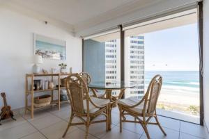 a dining room with a table and chairs and the beach at Longbeach Luxe, Surfers Paradise in Gold Coast