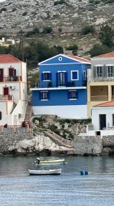 een blauw gebouw met boten in het water bij Porphyra Studio in Halki