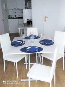 une table et des chaises blanches avec des assiettes et des verres bleus dans l'établissement DIVINE MARINA vue mer - Piscines, à Dives-sur-Mer 25 autres photos