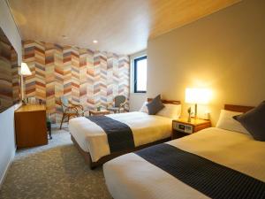 una camera d'albergo con due letti e un tavolo con sedie di Hotel New Gaea Itoshima a Itoshima