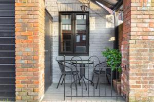 a patio with a table and chairs on a brick wall at Lovely 1-Bedroom GF flat in Canford Cliffs in Canford Cliffs