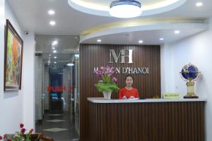 una mujer parada en un mostrador en el vestíbulo del hotel en MH Hanoi Hotel, en Hanói