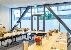 una sala conferenze con tavoli, sedie e finestre di Sudima Christchurch City a Christchurch