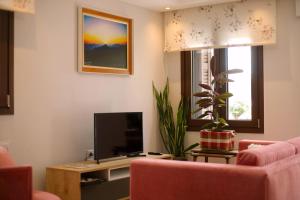 ein Wohnzimmer mit einem TV und einer rosa Couch in der Unterkunft Το Σπίτι της Ευτυχίας Σουίτα in Karpenisi