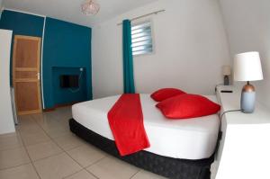 a bedroom with a white bed with red pillows at le raphael ( chambre piscine) in Saint-Joseph