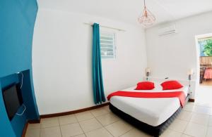 una camera da letto con un letto con cuscini rossi e una TV di le raphael ( chambre piscine) a Saint-Joseph