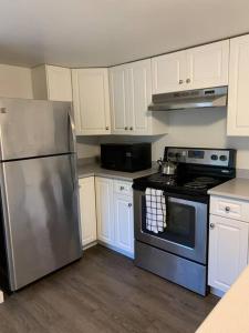 a kitchen with white cabinets and a stainless steel refrigerator at Cosy country mobile home on 18 acres farm sleeps 5 in Port Alberni