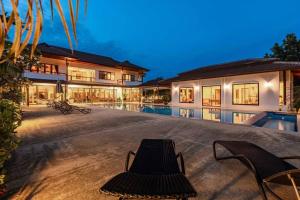 a house with a swimming pool and two chairs at Large 6 Bed Luxury Villa on the Golf Course PHJ in Cha Am