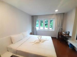 a bedroom with a white bed with a bow on it at Bayview Hotel & Apartments in Vung Tau