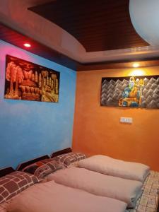 2 Betten in einem Zimmer mit Gemälden an der Wand in der Unterkunft Shri Narayan Tourist lodge & Chandica hotel in Trijugi Nārāyan
