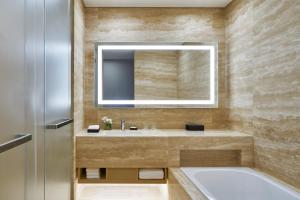 y baño con bañera, lavabo y espejo. en Marriott Jeju Shinhwa World Hotel, en Seogwipo