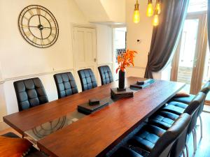 a dining room table with chairs and a large clock on the wall at Squirrel Lodge in Keswick