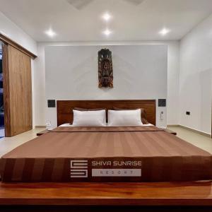 Schlafzimmer mit einem großen Bett mit einem Kopfteil aus Holz in der Unterkunft Shiva Sunrise Resort in Hikkaduwa