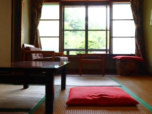 ein Wohnzimmer mit einem Tisch und einem großen Fenster in der Unterkunft Minshuku Sawaguchi in Agematsu