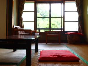 a living room with a table and a large window at Minshuku Sawaguchi in Agematsu