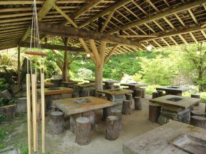 eine Gruppe von Tischen und Bänken unter einem Pavillon in der Unterkunft Minshuku Sawaguchi in Agematsu