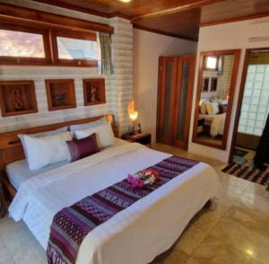 um quarto com uma grande cama branca com flores em Gili T Sugar Shack em Gili Trawangan