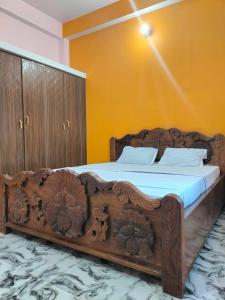 Cette chambre dispose d'un grand lit en bois et de murs jaunes. dans l'établissement Lagnalaya- Your Next Home, à Rajgir