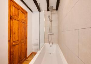 a bath tub in a room with a wooden door at Coach House in Llanfachreth