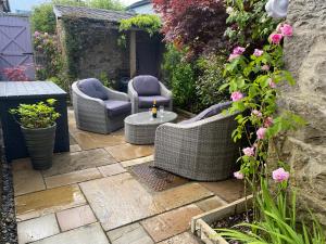 a patio with wicker chairs and a table and flowers at Meadowbank Cottage in Carnforth