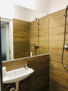 ein Bad mit einem Waschbecken, einer Dusche und einem Spiegel in der Unterkunft Central Petit Room in Braşov